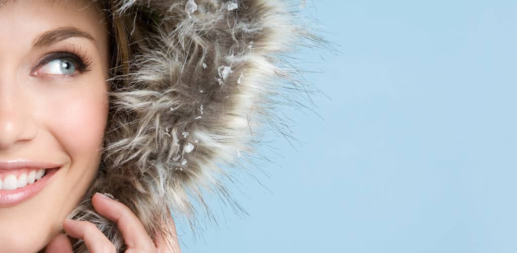 smiling young woman in fur hat touching her face