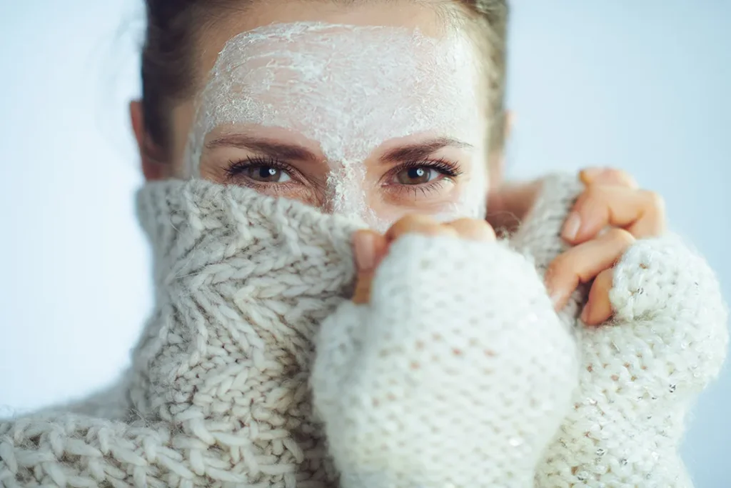 Woman hiding her face behind her jumper collar